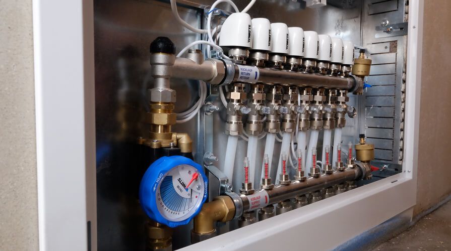 Installed heating circuit manifold with 8 heating circuits, equipped with the iDROSET CF balancing valve for hydronic balancing, in the new construction of a 105 m² bungalow in Bruchweiler, Rhineland-Palatinate, Germany.