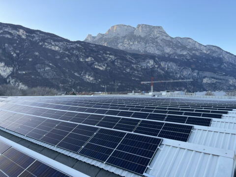 Photovoltaic system on industrial rooftop with Trentino mountains in the background
