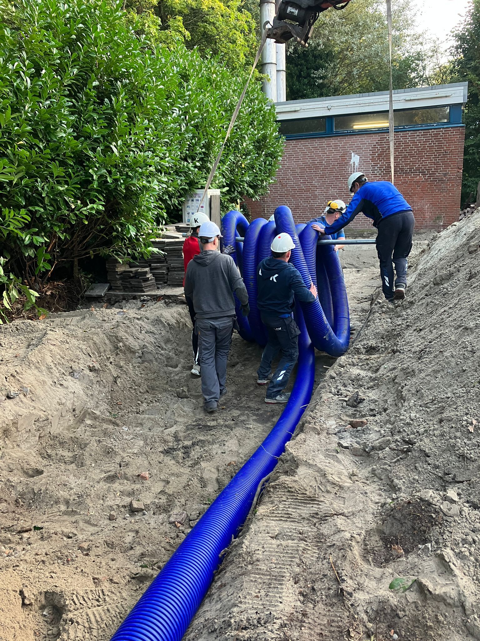 Workmen roll out microflex pipes