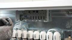 Ein Installateur verkabelt den Watts Vision Regelverteiler WFC-03 mit Stellantrieben 26LC, die auf dem Heizkreisverteiler HKV2013AF installiert sind.